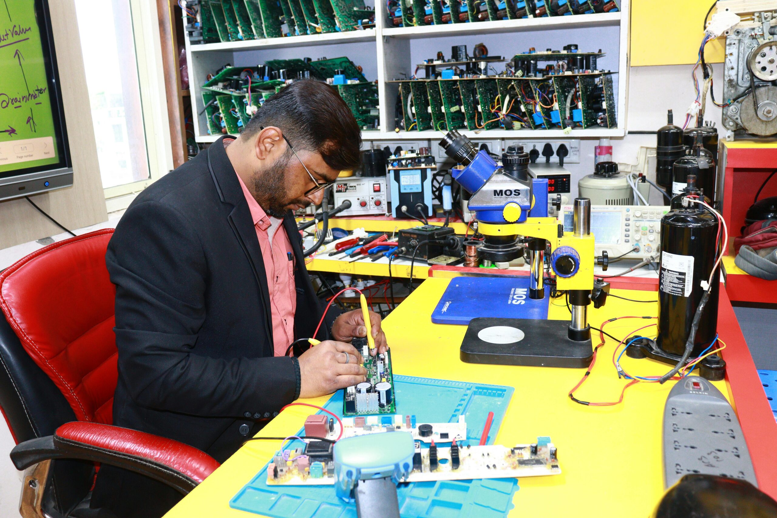A focused technician repairs a circuit board in a high-tech electronics workshop.